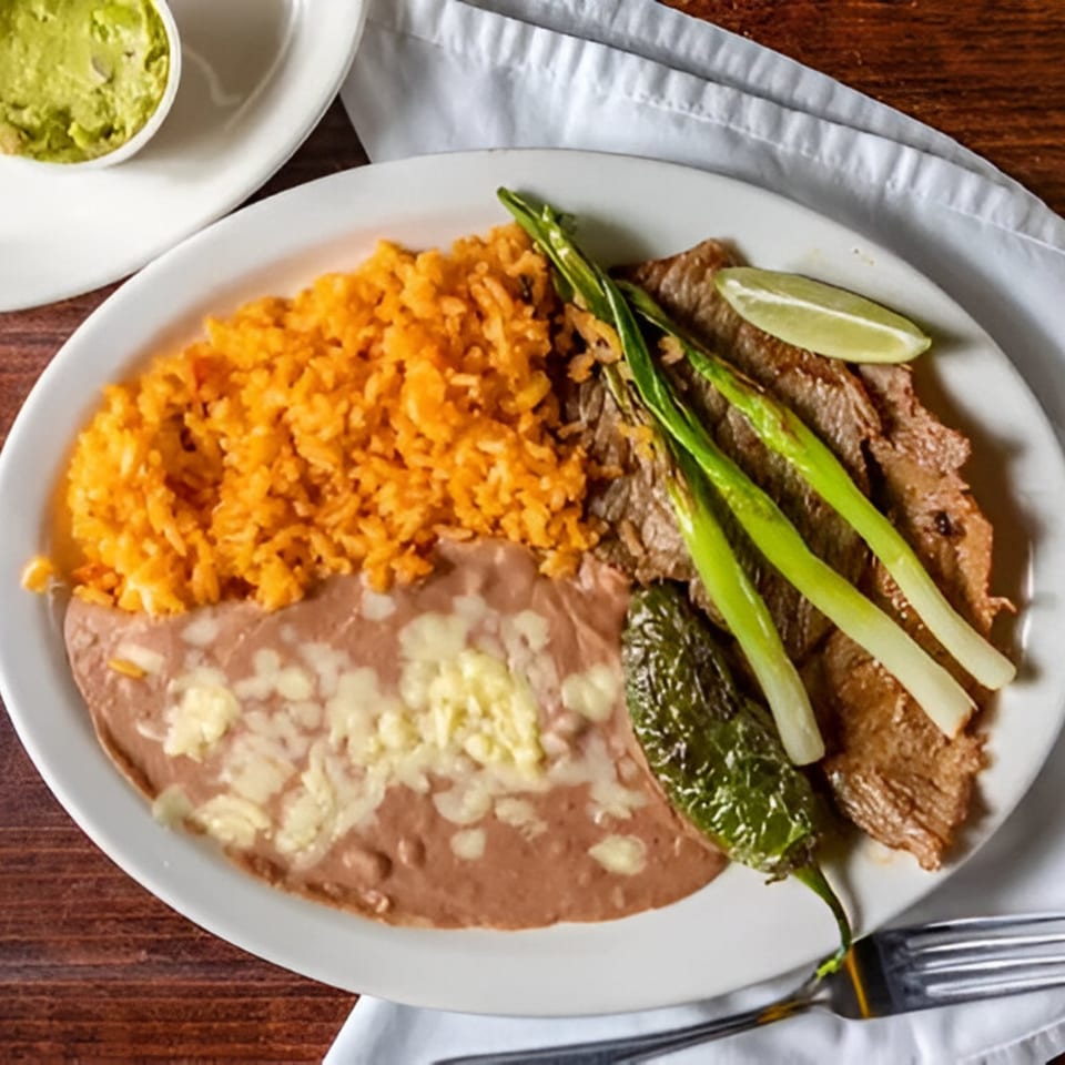 Los Mayas Mexican dish with steak, rice, refried beans, grilled onions, and a chile.
