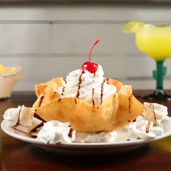 Fried ice cream in a crispy shell with whipped cream, chocolate drizzle, and a cherry.
